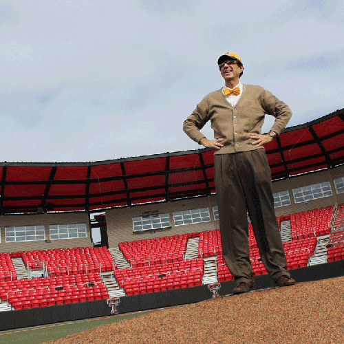 Jorge standing on a baseball field with empty red sit in the background