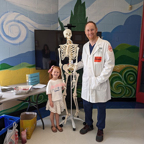 Tyson wearing doctors coat with his daugther and a fake skeleton between them